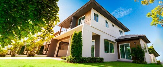 foto de um sobrado em um dia ensolarado e um jardim à frente, com a grama bem aparada